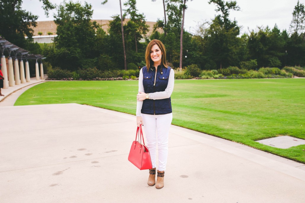 red bag navy quilted vest white jeans